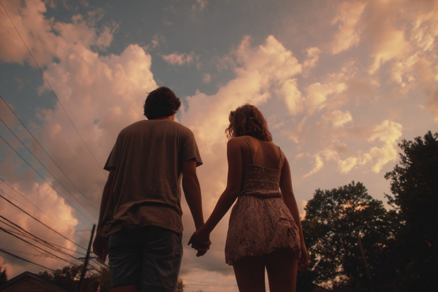 Ein Mann und eine Frau halten Händchen. Hinter ihnen ist der Himmel zu sehen.